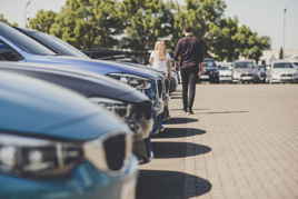 Car buyers walk across a dealership forecourt